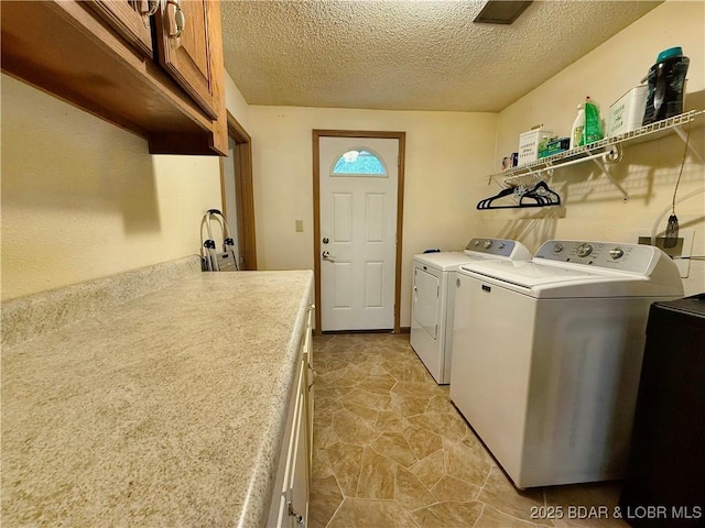 washroom featuring washing machine and dryer, cabinet space, and a textured ceiling
