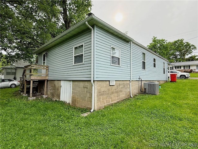 view of side of home featuring a yard, central AC, and a wooden deck