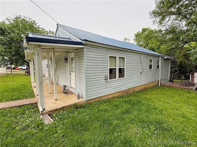 view of side of property featuring a yard and metal roof