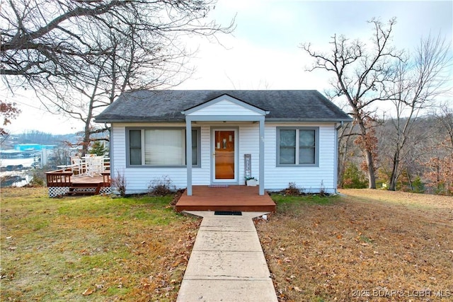 bungalow-style house with a front lawn, a wooden deck, and roof with shingles