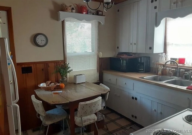 kitchen featuring a sink, white cabinets, a wainscoted wall, light countertops, and black microwave