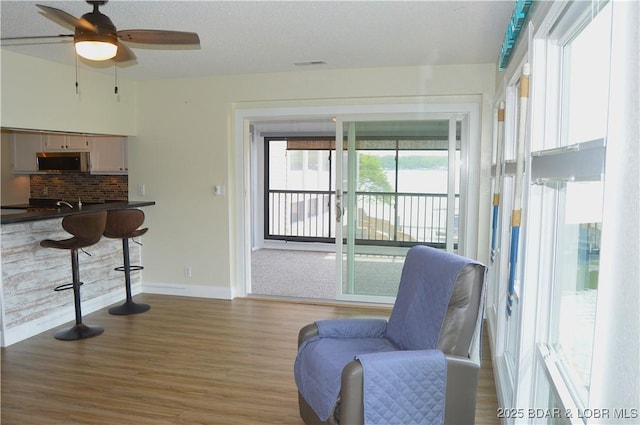 living area with wood finished floors, baseboards, and a ceiling fan