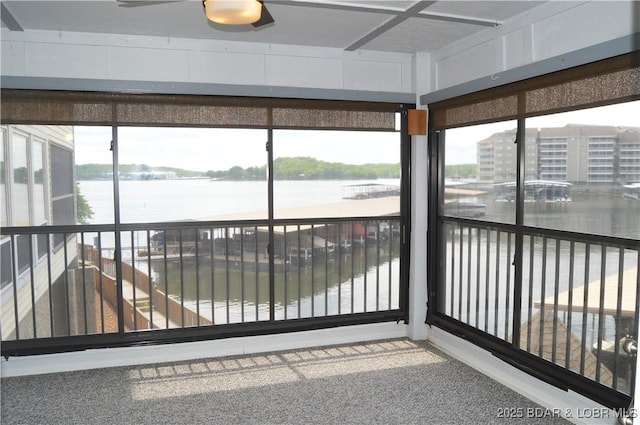unfurnished sunroom featuring a water view, plenty of natural light, and carpet floors