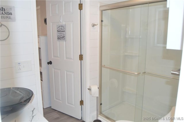 bathroom with a shower stall and wood finished floors