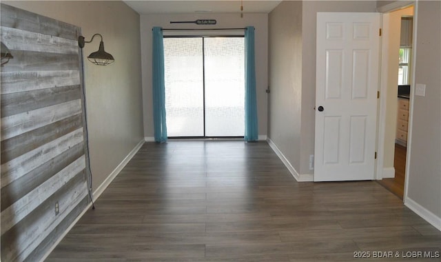 unfurnished room featuring healthy amount of natural light, baseboards, and dark wood finished floors