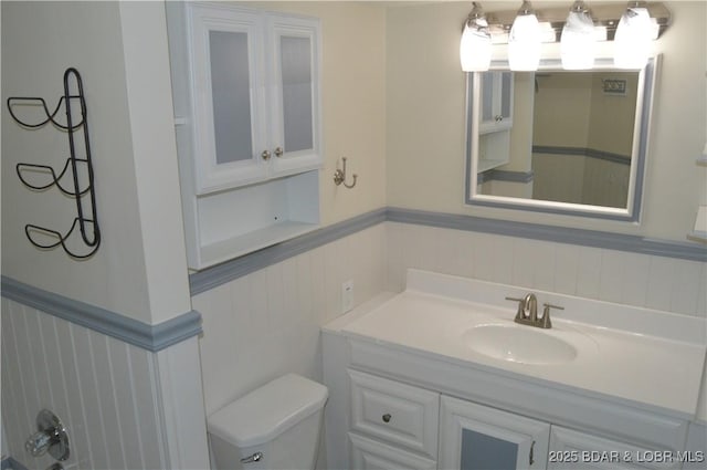 bathroom with wainscoting, toilet, and vanity