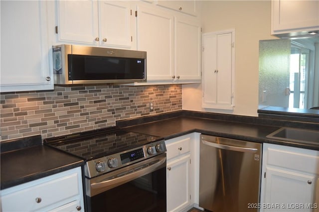 kitchen featuring appliances with stainless steel finishes, dark countertops, white cabinetry, and backsplash