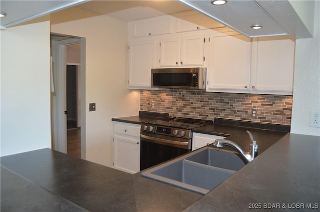 kitchen with stainless steel appliances, white cabinetry, dark countertops, backsplash, and recessed lighting