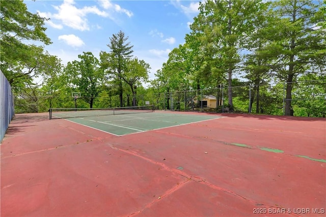 view of tennis court featuring fence and view of scattered trees