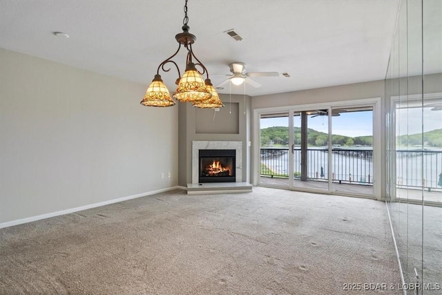 unfurnished living room with carpet, baseboards, ceiling fan, a water view, and a high end fireplace