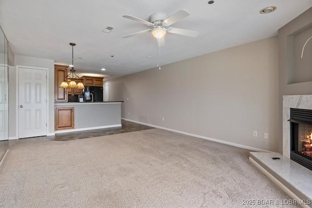 unfurnished living room featuring dark colored carpet, a premium fireplace, baseboards, ceiling fan, and recessed lighting