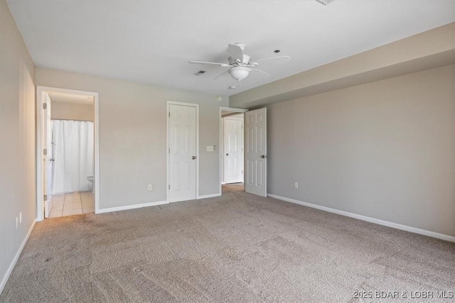 unfurnished bedroom featuring carpet floors, baseboards, ensuite bath, and a ceiling fan