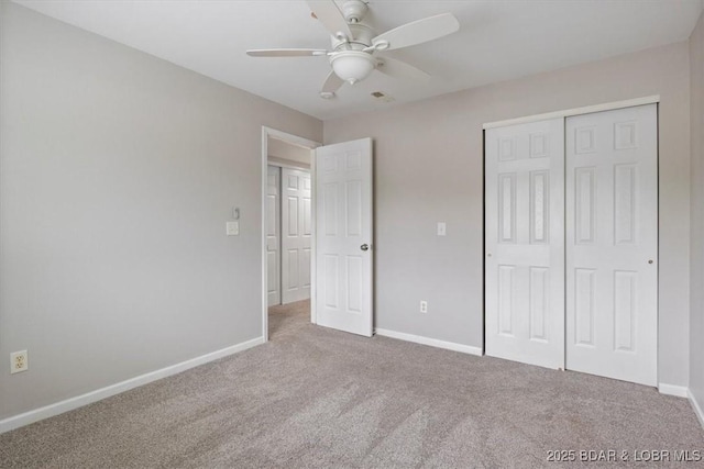 unfurnished bedroom featuring carpet, baseboards, a closet, and a ceiling fan
