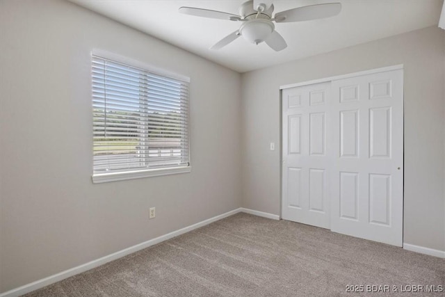 unfurnished bedroom with carpet floors, a closet, baseboards, and a ceiling fan