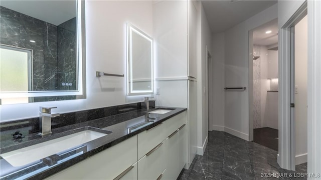 bathroom featuring marble finish floors, double vanity, and baseboards
