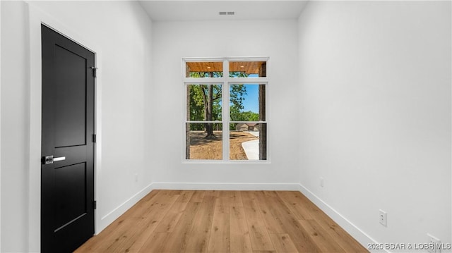 spare room featuring light wood-type flooring and baseboards
