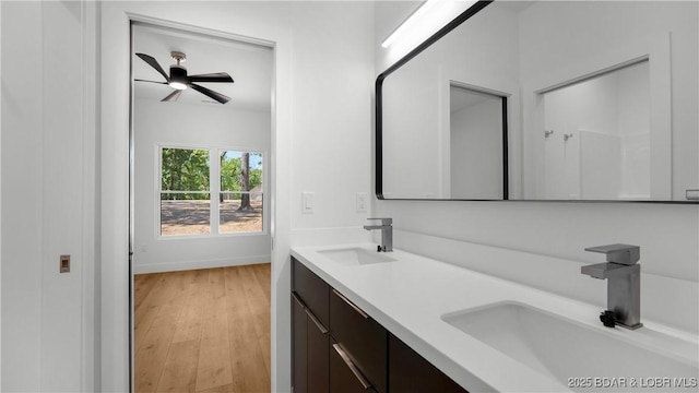 full bath with ceiling fan, wood finished floors, double vanity, and baseboards