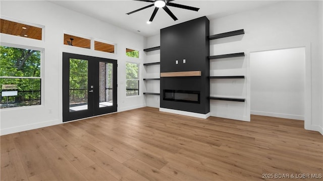 unfurnished living room featuring wood finished floors, a glass covered fireplace, and ceiling fan