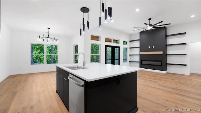 kitchen featuring a sink, stainless steel dishwasher, dark cabinetry, hanging light fixtures, and a chandelier