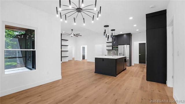 kitchen with stainless steel appliances, light countertops, dark cabinets, a sink, and a chandelier