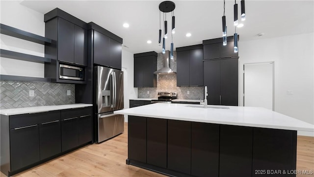 kitchen featuring stainless steel appliances, a sink, open shelves, dark cabinetry, and decorative light fixtures
