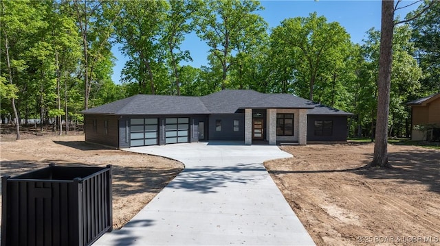 prairie-style home featuring an attached garage, driveway, and roof with shingles
