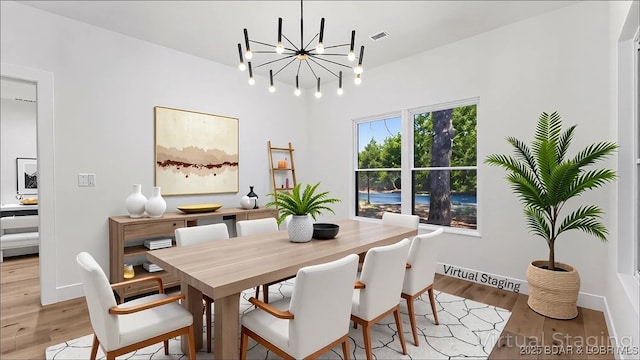 dining space with light wood-style flooring, a chandelier, and baseboards