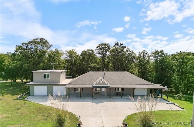 view of front of home with driveway, a front lawn, covered porch, and view of wooded area