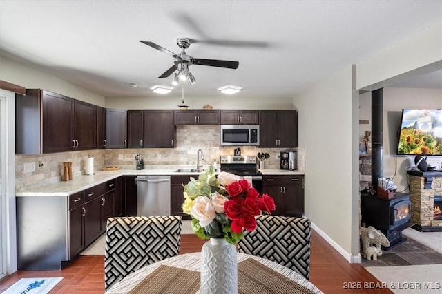 kitchen featuring appliances with stainless steel finishes, a sink, dark brown cabinets, and light countertops