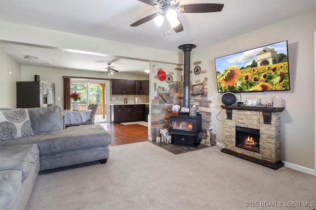 carpeted living room with ceiling fan and a wood stove