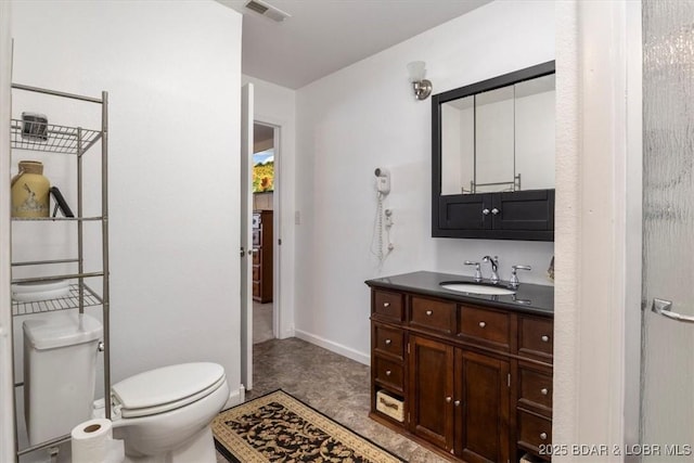 bathroom featuring toilet, vanity, and baseboards
