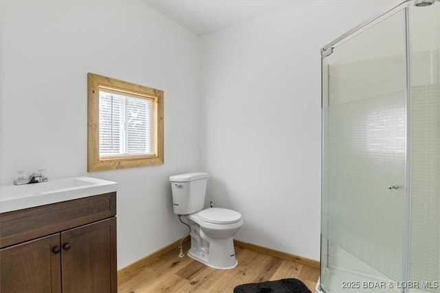 full bath with wood finished floors, a shower stall, toilet, vanity, and baseboards