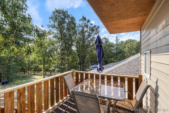 deck with outdoor dining area and view of scattered trees