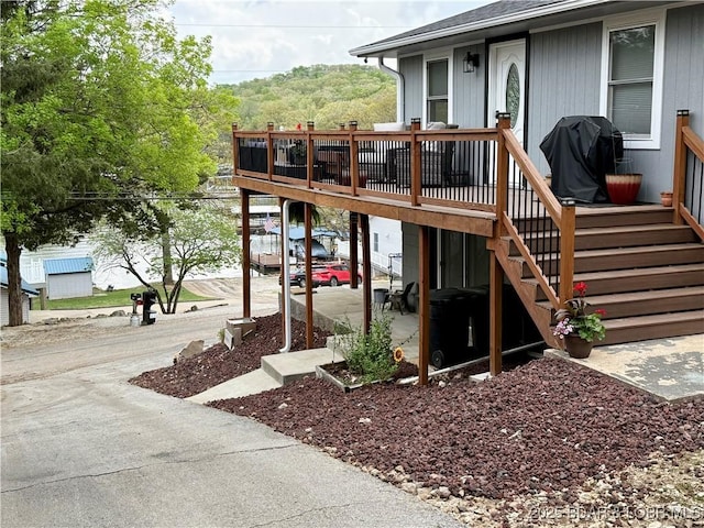 entrance to property featuring a deck and a shingled roof