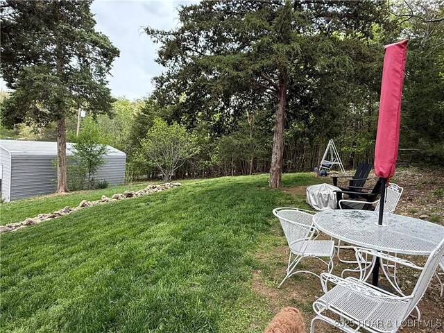 view of green lawn featuring an outbuilding and a storage unit