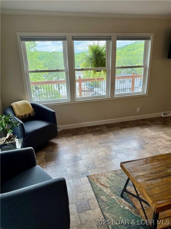 living area with baseboards and crown molding