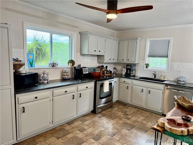 kitchen featuring stainless steel appliances, dark countertops, backsplash, ornamental molding, and ceiling fan