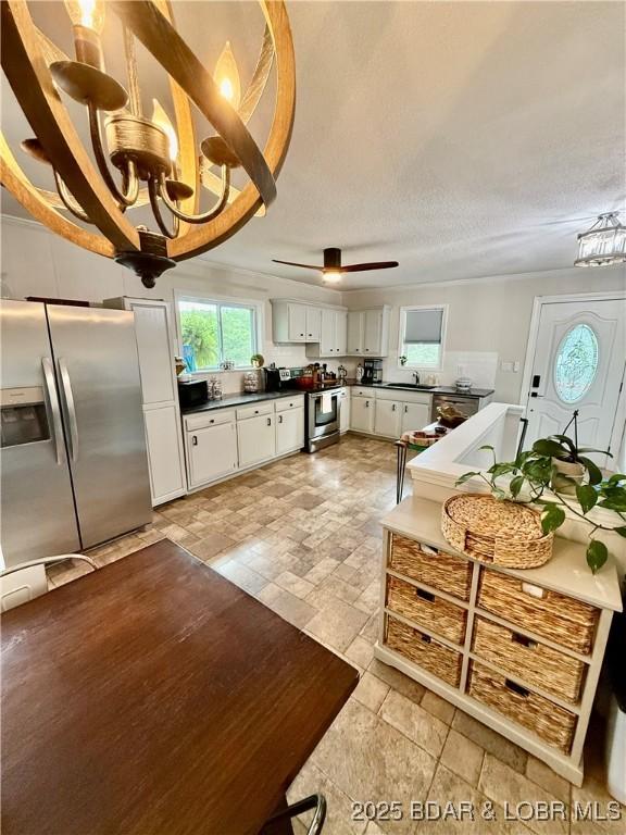 kitchen with appliances with stainless steel finishes, a chandelier, dark countertops, and white cabinetry