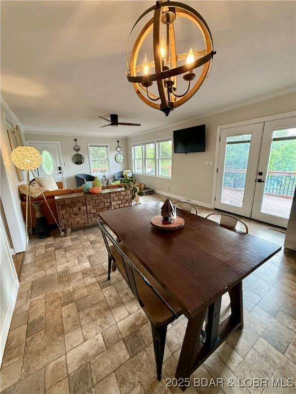 dining room featuring stone tile floors, a chandelier, crown molding, french doors, and baseboards