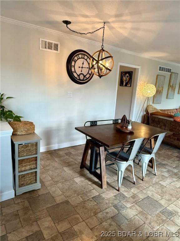 dining space featuring ornamental molding, a chandelier, dark stone finish flooring, and baseboards