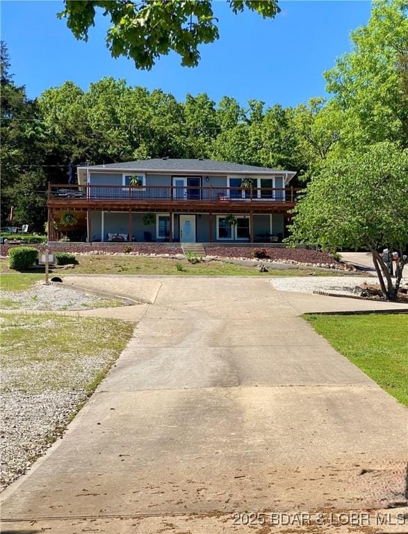 view of front facade featuring concrete driveway, a front yard, and a deck