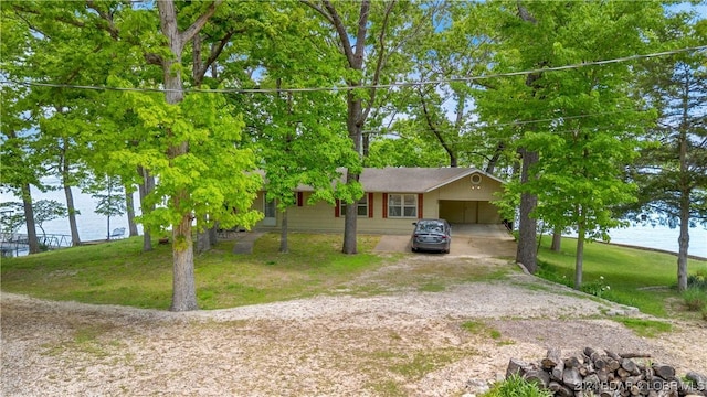 ranch-style home with driveway, a water view, a front yard, and an attached carport
