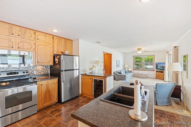 kitchen with stainless steel appliances, wine cooler, a sink, open floor plan, and backsplash