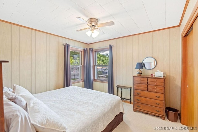 carpeted bedroom featuring crown molding, wood walls, a closet, and ceiling fan