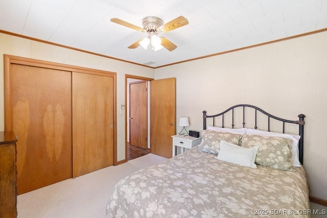 carpeted bedroom with ornamental molding, a closet, and a ceiling fan