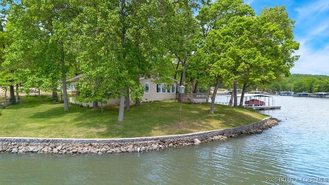 rear view of house with a water view and a lawn