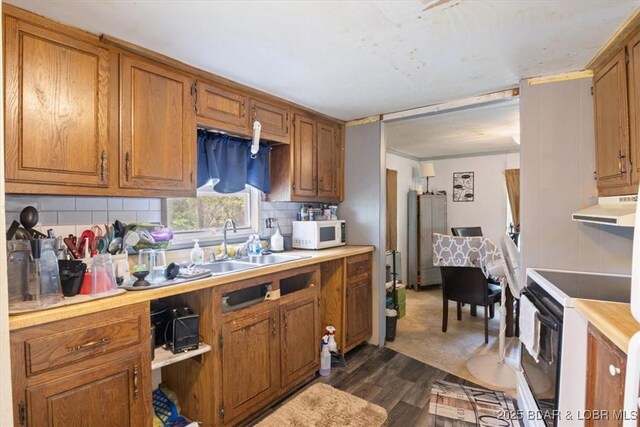 kitchen featuring white appliances, range hood, brown cabinetry, and dark wood-style flooring