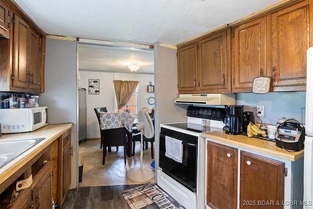 kitchen featuring white microwave, range with electric cooktop, ventilation hood, light countertops, and brown cabinets