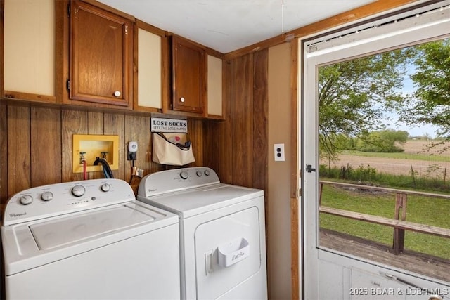 washroom featuring cabinet space, independent washer and dryer, and wood walls