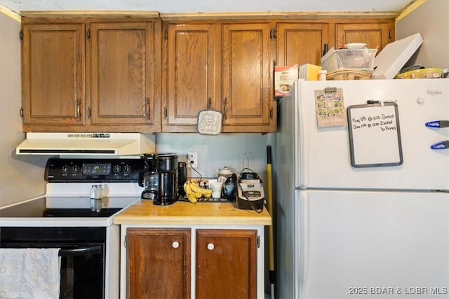 kitchen featuring freestanding refrigerator, range with electric cooktop, under cabinet range hood, and brown cabinets